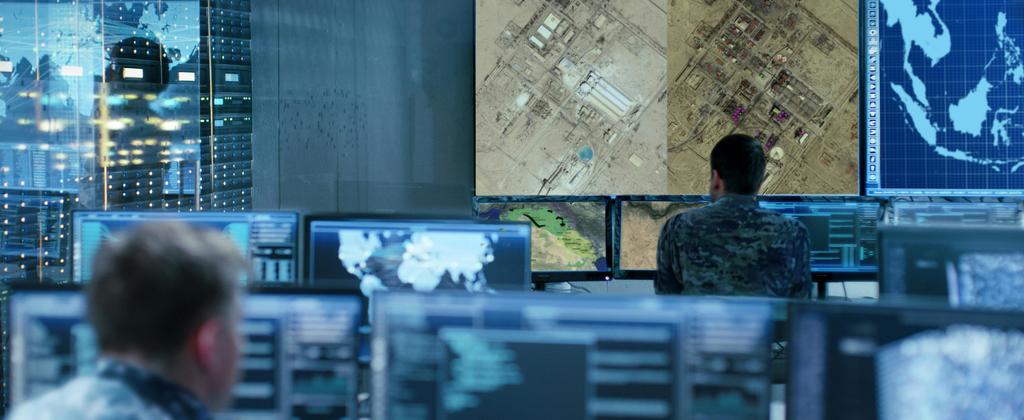 Controller collaborating on computer screens in a command centre, focused on their tasks.