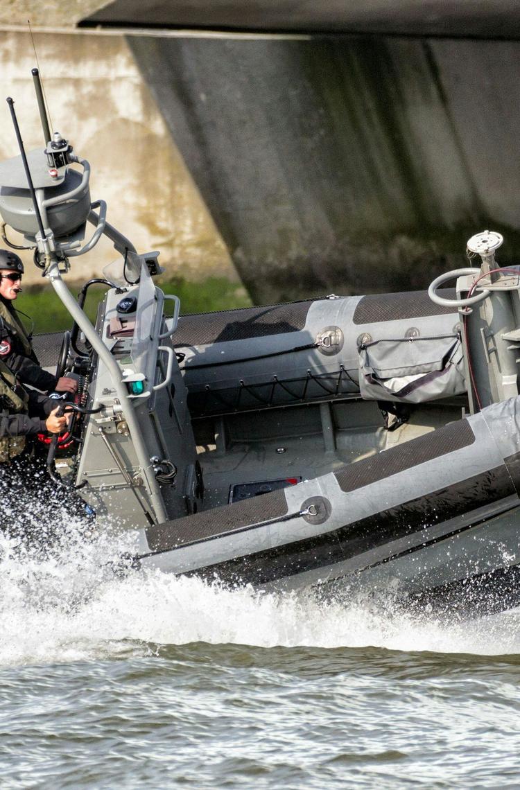 Military men navigating on a speed boat, monitoring coastal areas Military men navigating on a speed boat, monitoring coastal areas