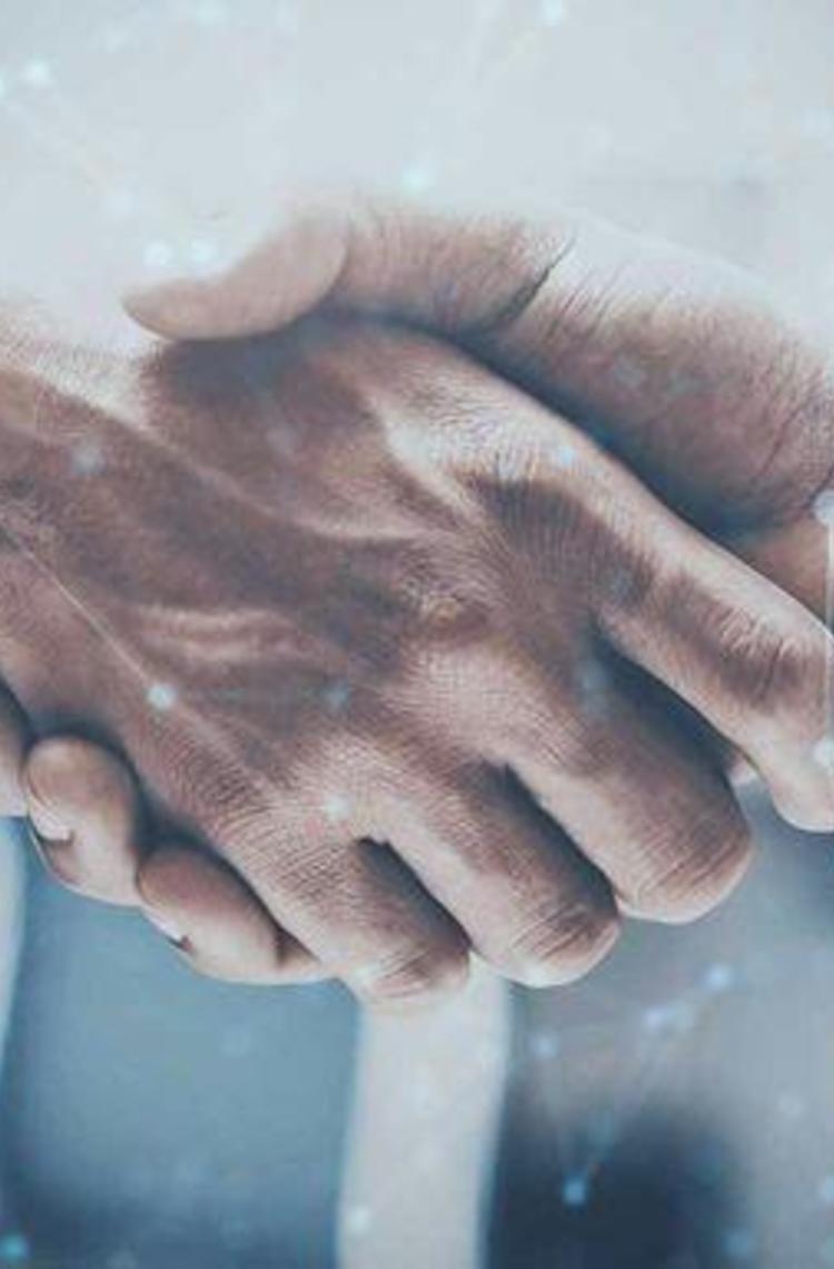 Close-up of a handshake from two men wearing business shirts. Around it you can see digital-looking dots and connecting lines. The image has a modern, technical and digital look and feel and is decorated in blue tones.